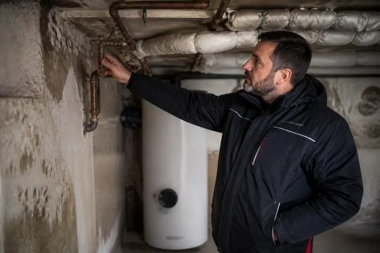 Technicien analysant l'installation de chauffage et l'isolation pour éviter une pompe à chaleur défectueuse.