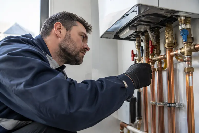 Technicien effectuant l'entretien annuel et la vérification des raccords d'une chaudière gaz