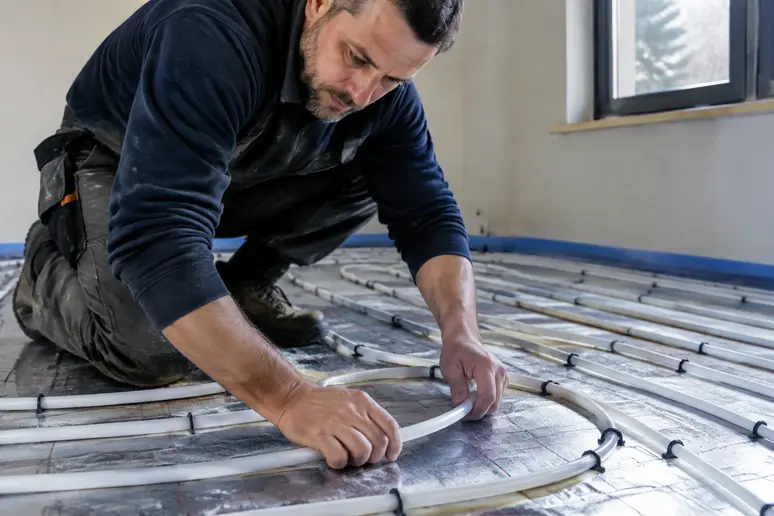Pose d'un plancher chauffant à eau sur des panneaux isolants dans une pièce en rénovation