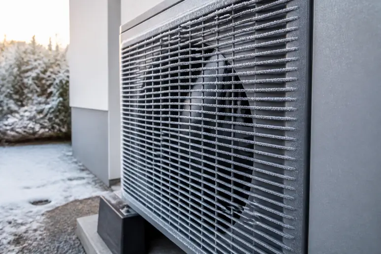 Givre sur la grille de l'unité extérieure d'une pompe à chaleur en hiver