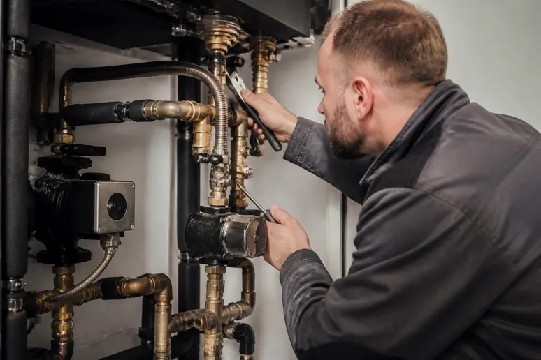 Technicien verifiant les raccordements hydrauliques d une installation de chauffage
