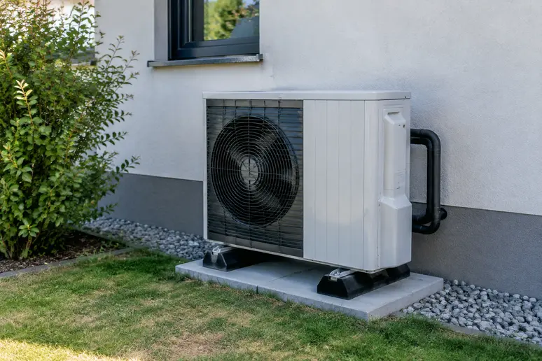 Unité extérieure de pompe à chaleur installée dans le jardin d'une maison individuelle