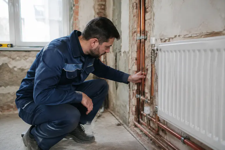 Artisan vérifiant une installation de chauffage lors de travaux de rénovation
