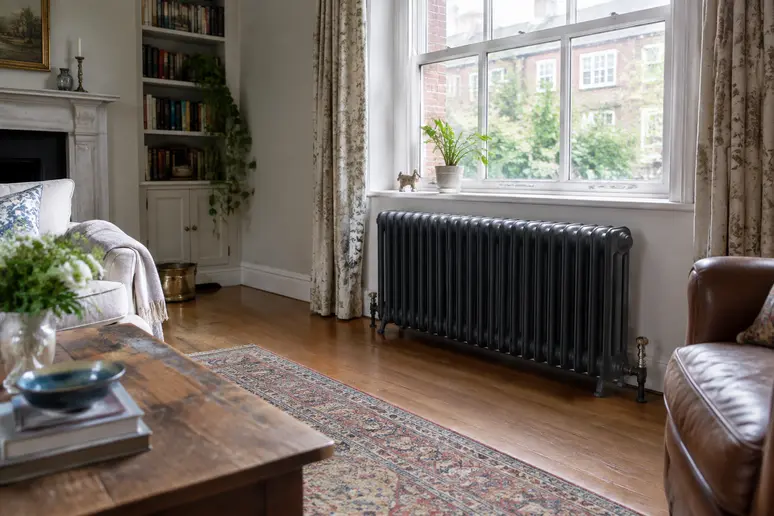 Grand radiateur en fonte installé sous une fenêtre dans une pièce de vie