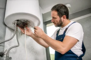 Un plombier installe une résistance chauffe-eau dans un local technique bien éclairé.