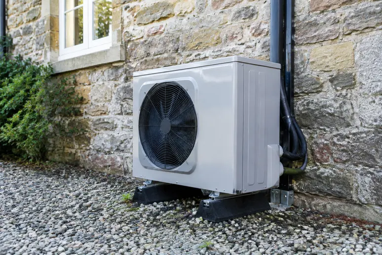 Unite exterieure de pompe a chaleur installee sur le mur d une maison ancienne