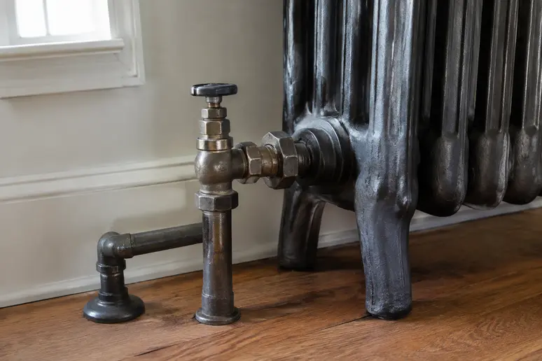 Tuyaux de raccordement d'une pompe à chaleur sur des radiateurs en fonte dans une maison ancienne