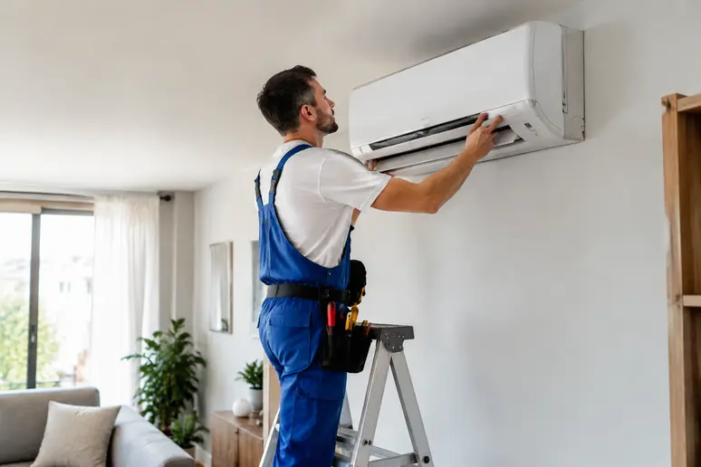 Technicien posant une unité intérieure de pompe à chaleur réversible dans un salon lumineux