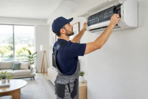 Un technicien effectue la maintenance d'une pompe à chaleur réversible fixée au mur du salon.